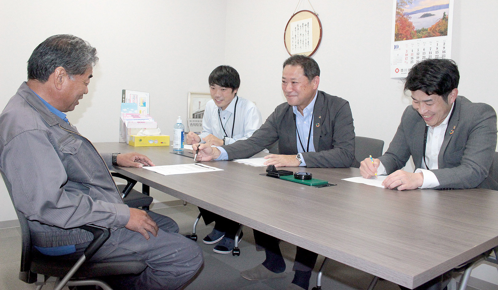 建設会社代表（左）と商談する大山支店長（左から3人目）ら（10月25日、円座支店）