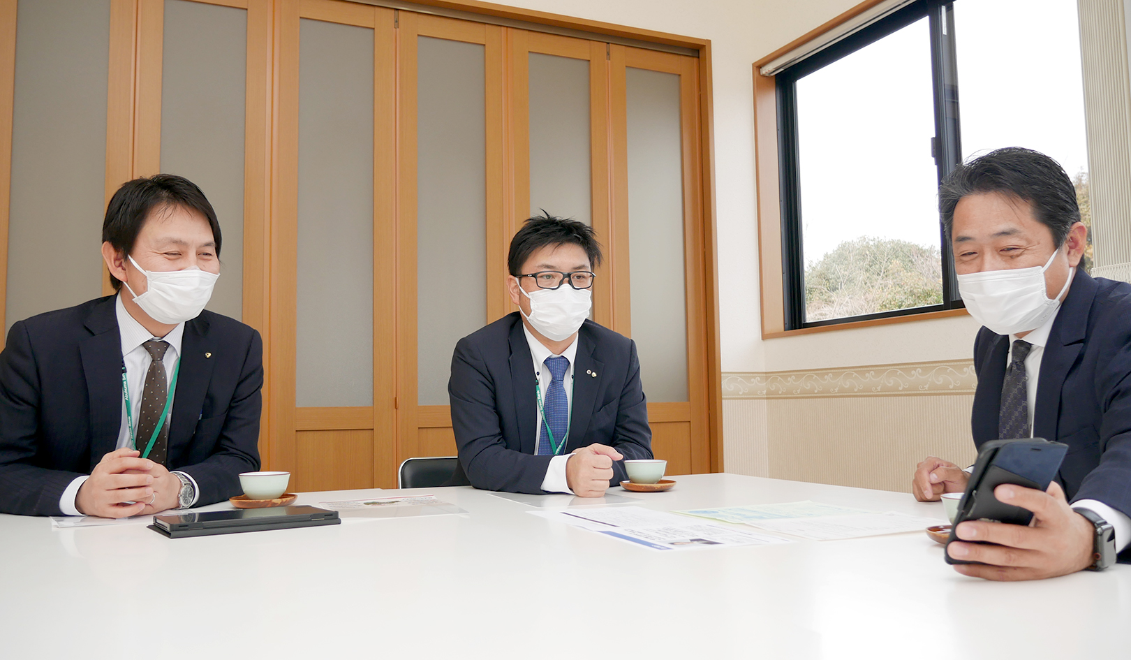 取引先の「東北工業建設」を訪問し、戸川聡社長（右）と情報交換する森川支店長（中央）と岡田寛・業務推進部営業推進課長（2月17日、浪江町内）