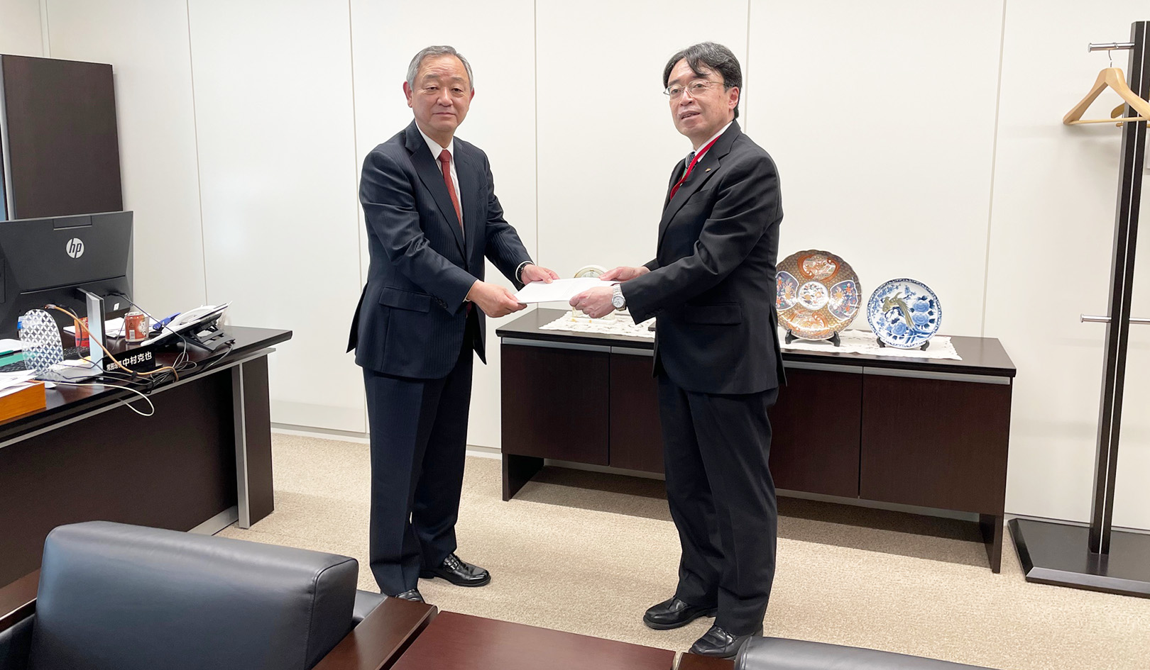 有識者会議のコーディネーターを務めた川瀬透氏（右）から答申を受け取る柳沢会長（4月21日、全国信用組合会館）