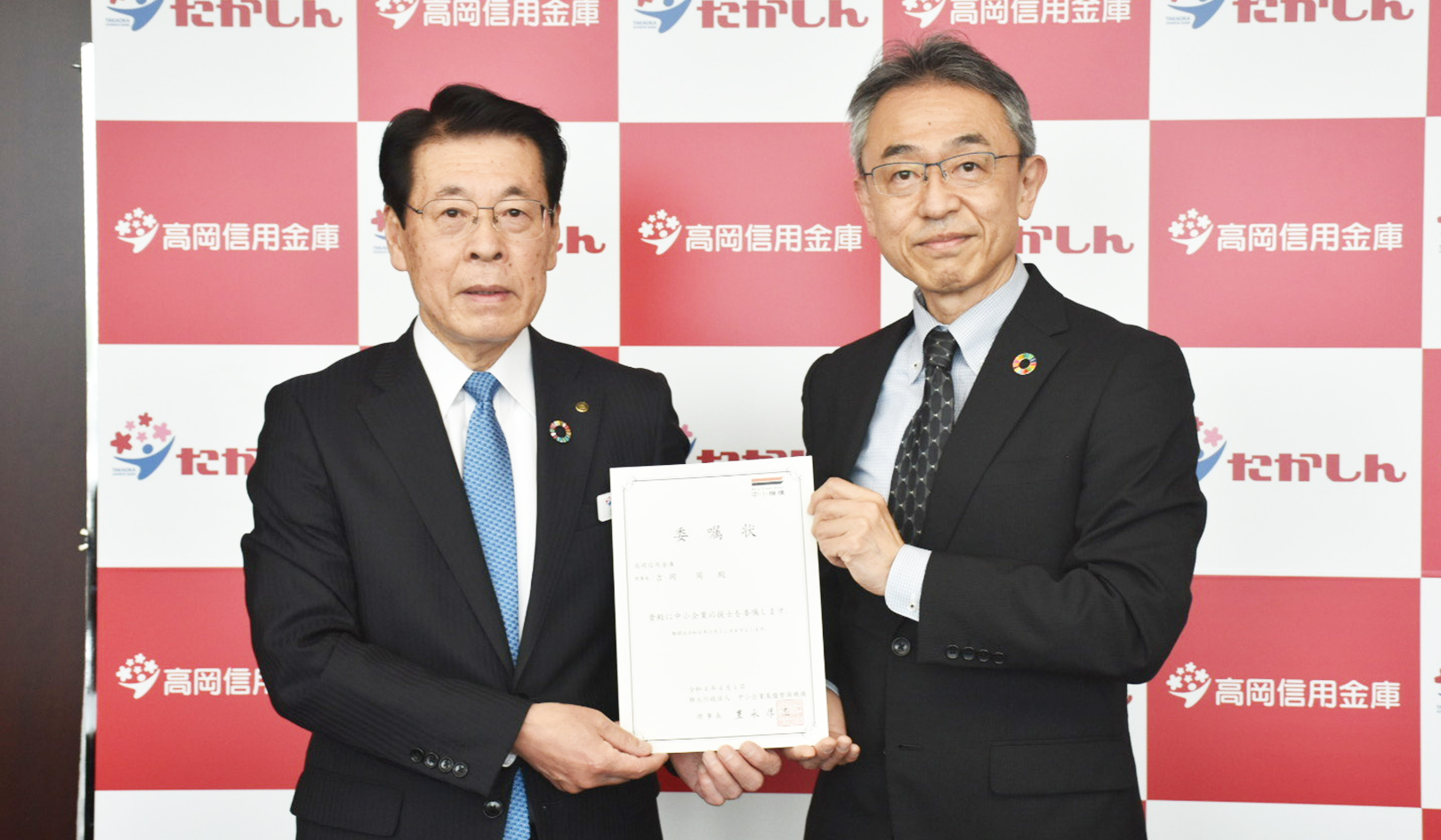 委嘱状を掲げる吉岡理事長(左)と笹岡健治北陸本部部長(4月27日、高岡信金本店)