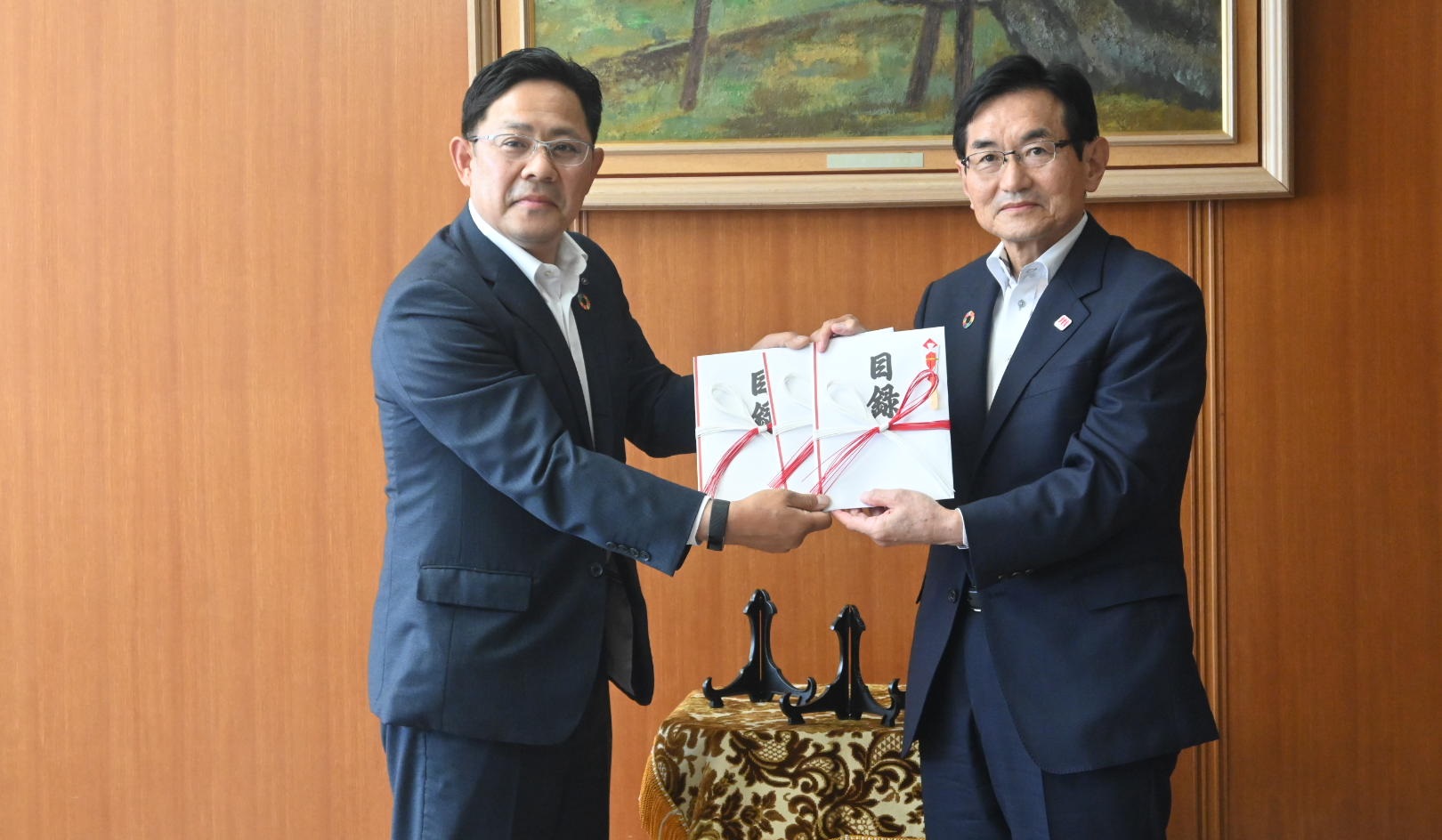 江口勝・福岡県副知事に目録を手渡す成瀬常務執行役員（左、５月19日、福岡県庁）