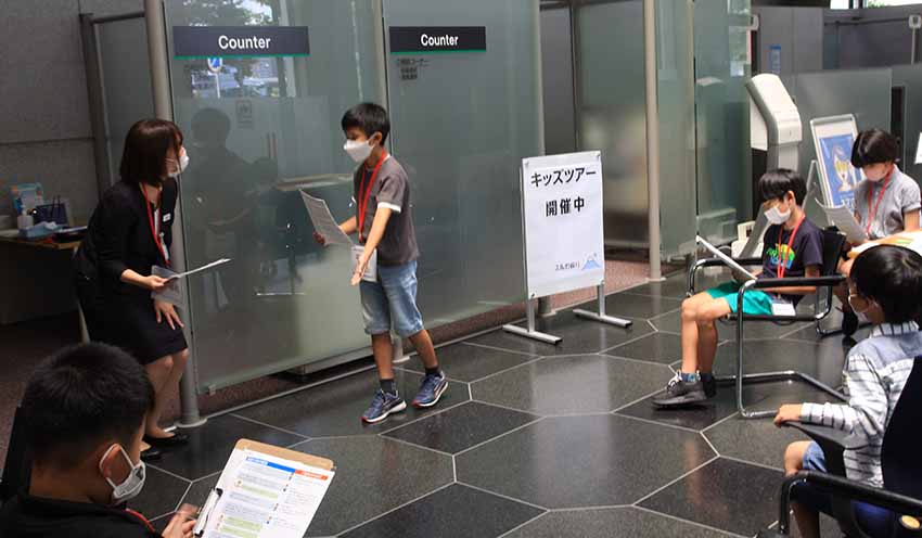 来店客役の行員を、緊張しながら案内する地元小学生(8月5日、スルガ銀本店営業部)