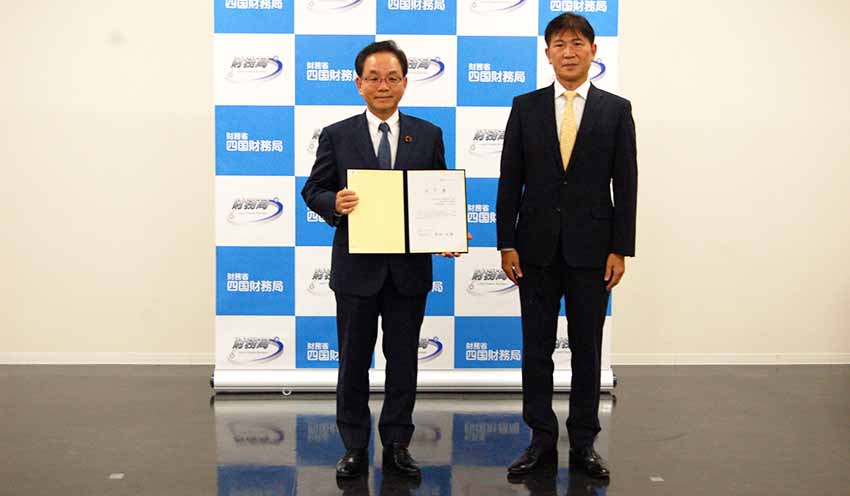 米田局長から認可書を受け取った三好頭取(左)(9月15日、四国財務局)