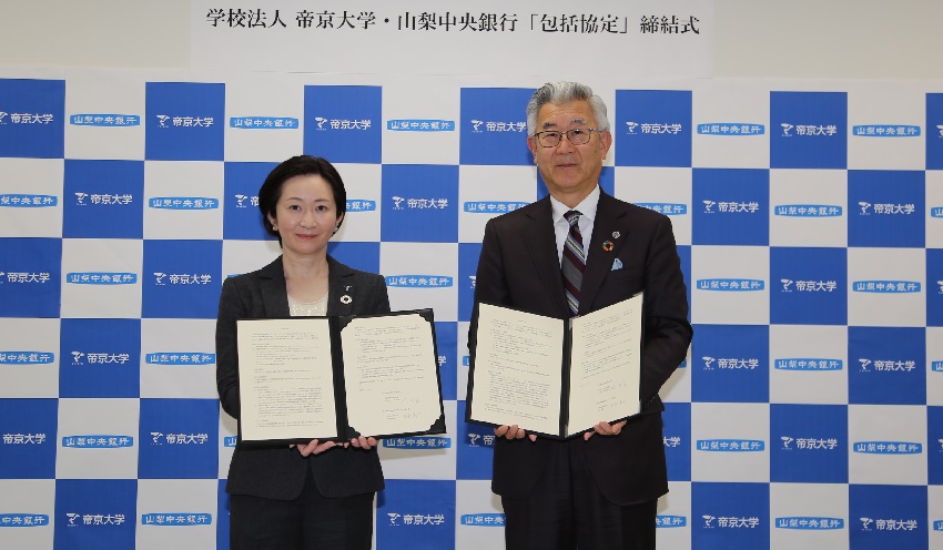 協定書を手にする山梨中央銀の関頭取(右)と帝京大の沖永寛子常務理事・副学長