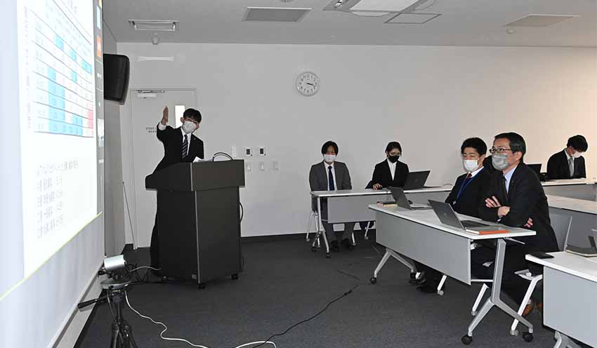 河原電子ビジネス専門学校の代表学生(左)が紺野・明屋書店社長(右)ら関係者に対し発表した(2月16日、松山市)