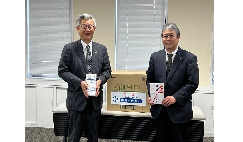 手島教育長（右）に再生紙の目録を贈り、現物を手にする関頭取（２月22日、山梨県