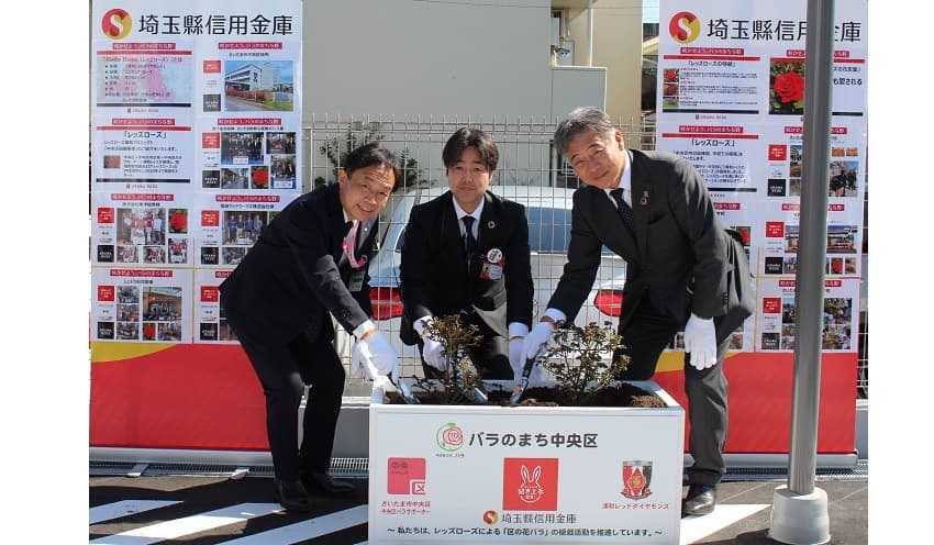 「レッズローズ」を植える(左から)中央区の近藤裕司区長、五十嵐支店長、浦和レッズの白戸秀和ホームタウン本部長(3月20日、同店駐車場)