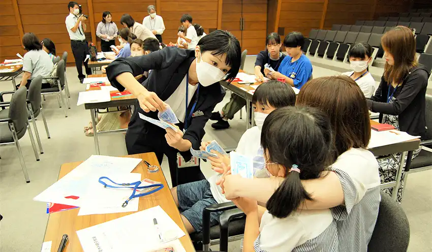 札勘定を教える百十四銀行員と説明を聞く親子（８月１日、百十四銀本店