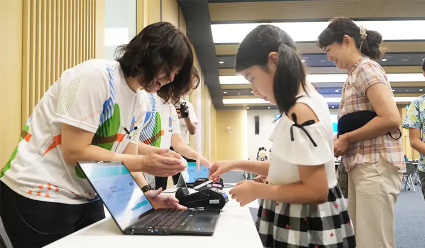 真剣な表情でタッチ決済を体験する子供たち（8月1日、北国銀本店）