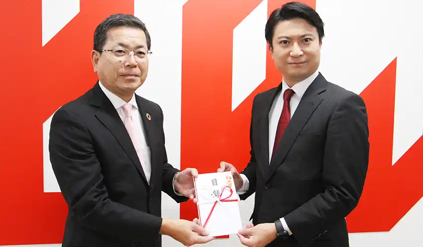 梅田頭取（左）がジェッツの田村社長に目録を手渡した（8月30日、千葉県船橋市の千葉ジェッツふなばし本社）
