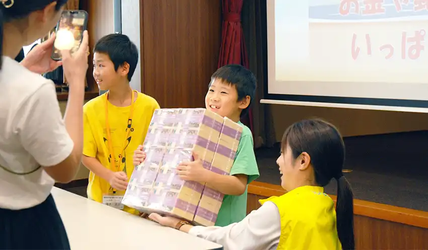 1億円の重さ体験をする子供たち（8月1日、東邦銀本店）