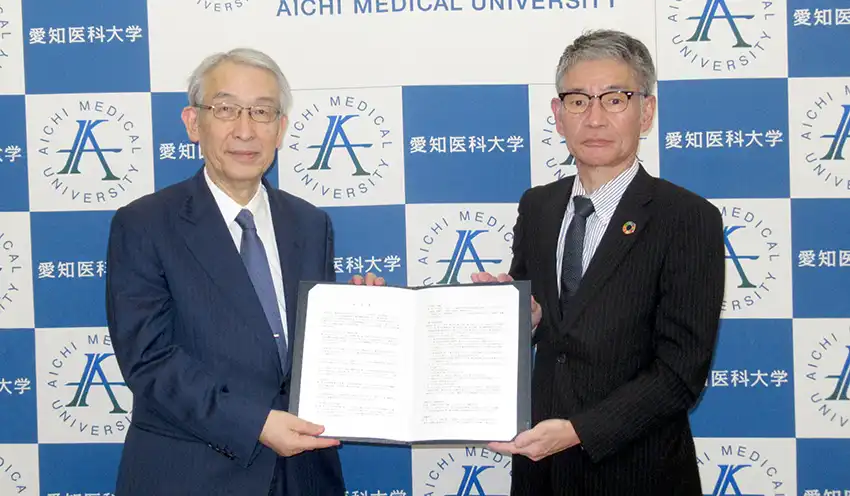 協定書を手にする愛知医科大の祖父江理事長（左）と名古屋銀の吉冨常務（右）