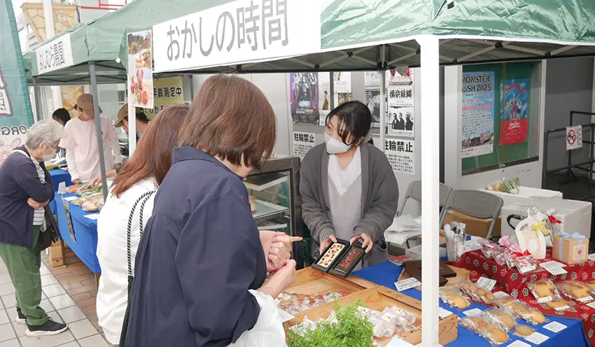 販売会の店頭に並んだ洋菓子や有機野菜などの商品に多くの人が足を止めた（5月26日、南新町5番地出張所前）