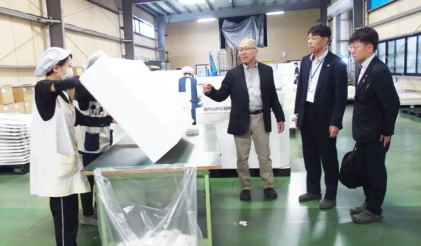 大橋紙器印刷の大橋一雄社長（右から3人目）から工場を案内される川島部長（同2人目）と鈴木力衛次長（5月21日、大橋紙器印刷本社）