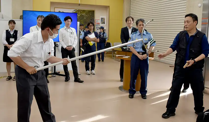 県警の担当者（右）からさすまたの使い方を学ぶ館山信金の職員（7月17日、千葉県館山市の本店）