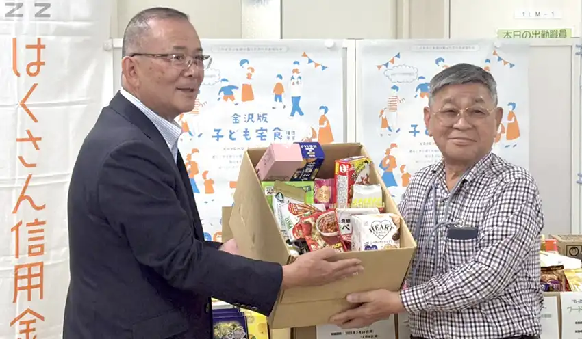 玉井理事長（左）が川元会長へ食品を手渡した（7月17日、米丸校下社会福祉協議会）