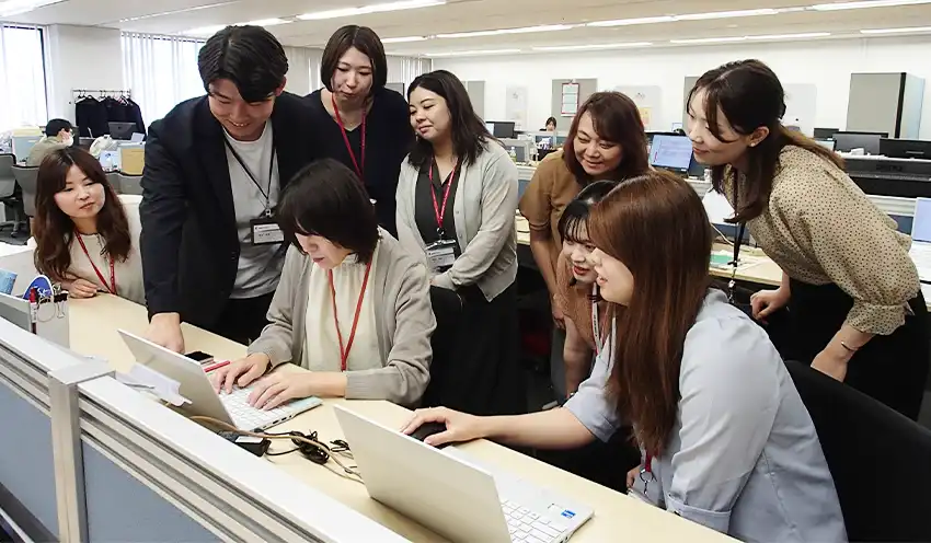 本社社員（左から2人目）の指導を受ける留学生（同3人目、7月18日、新宿本社内）