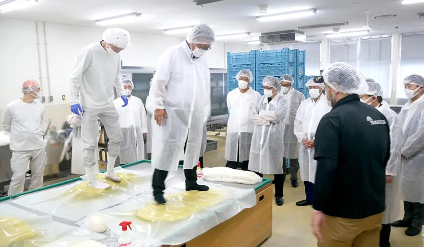 視察先の工場でうどん生地の足ふみ作業を体験する参加者（7月17日、高松市内）
