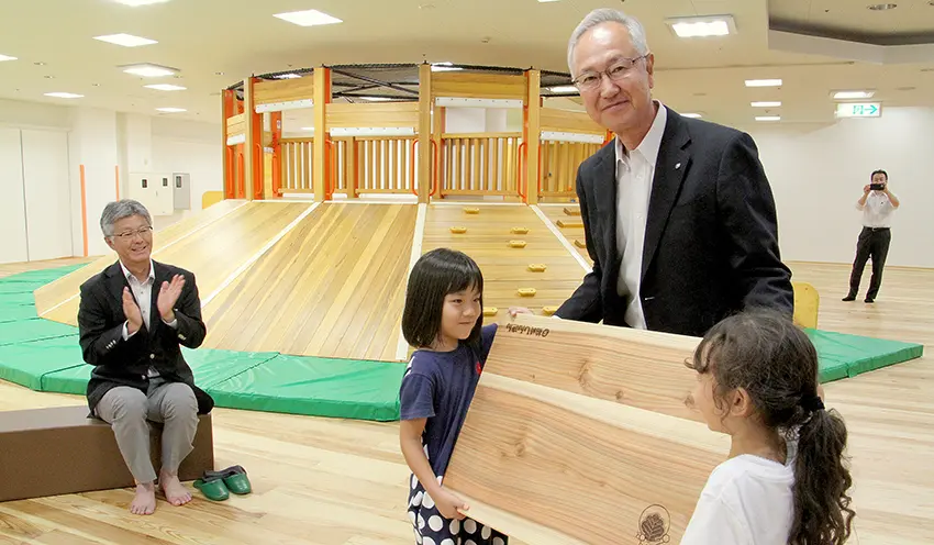 テーブルを手渡す小出理事長。左は櫻井雅浩・柏崎市長(7月25日、新潟県柏崎市の屋内遊び場「キッズマジック」)