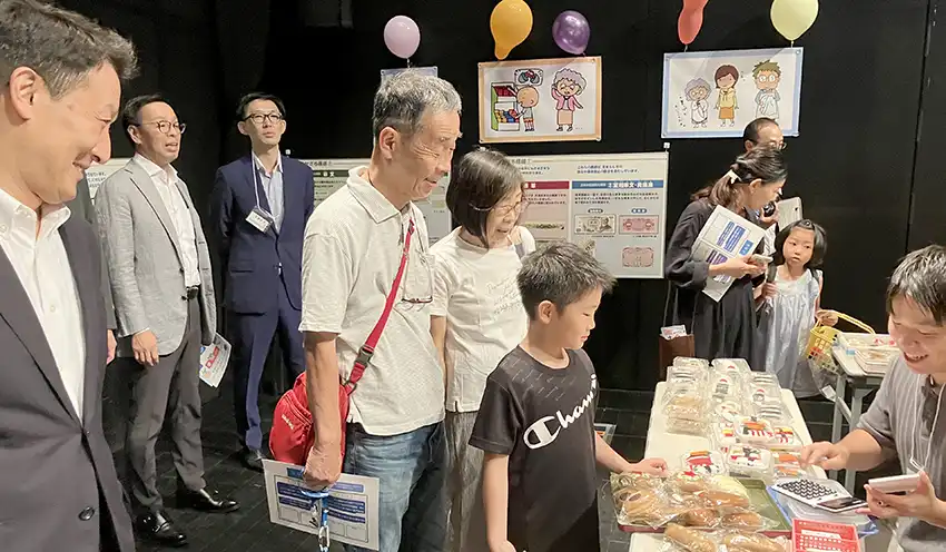 イベントに参加する子どもをほほ笑ましく見つめる米谷治彦・石川県銀行協会会長(北国銀行社長)(左、7月24日、金沢市内)