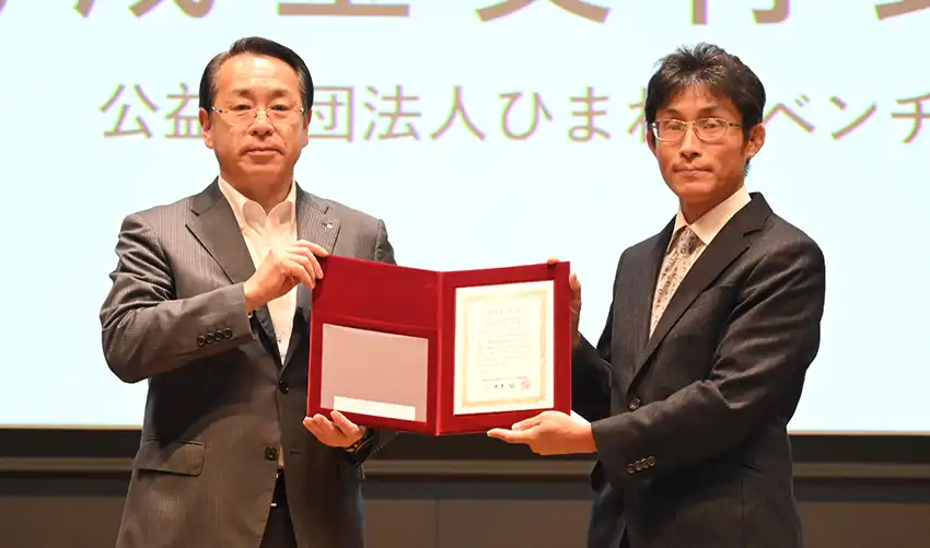 助成金を交付先企業に手渡す米本理事長（左、7月17日、千葉銀本店）