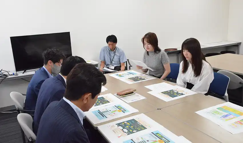 学生は遠賀信金の担当者にデザインの特長や思いなどを説明した（7月31日、九州産業大）