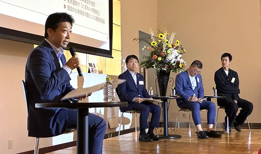 ワイエムゾップ設立10周年イベントで実績を説明する藏重嘉伸社長（左、７月10日、山口市内）