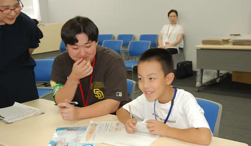 感想文に取り組む子ども（右）とスタッフの学生（7月31日、東北財務局）