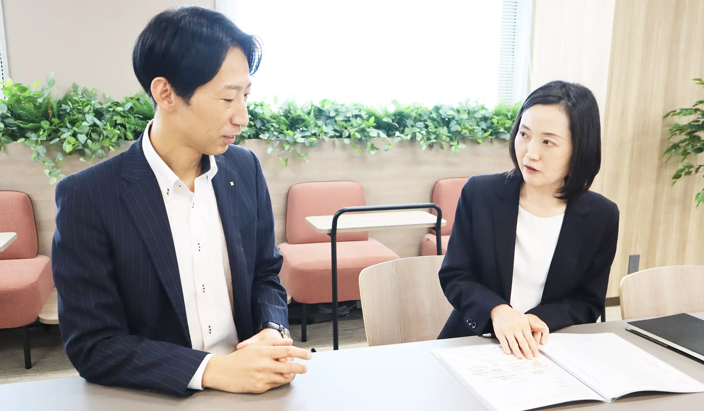阿見支店長（左）から営業や管理の手法を学ぶ赤尾副調査役（7月11日、アイザワ証券甲府支店）