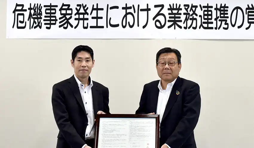 覚書を手にする（左から）湊支店長と鈴木理事長（8月20日、共立信組本部）