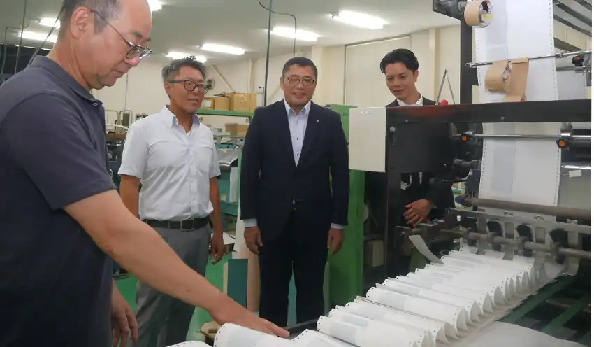 太陽技報堂の大坂常務取締役（左から2人目）から生産工程の説明を受ける原支店長（同3人目）と川崎紘平支店長代理（同4人目、8月19日、三木町内）
