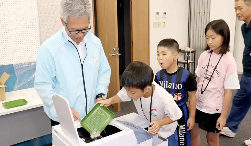 硬貨巻機に硬貨を投入する小学生ら(8月6日、かしんアイホールビル)