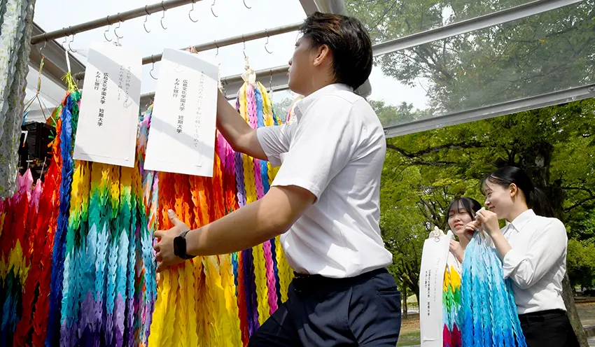 折り鶴をささげるもみじ銀の行員や広島文化学園短大の学生たち（8月4日、平和記念公園）