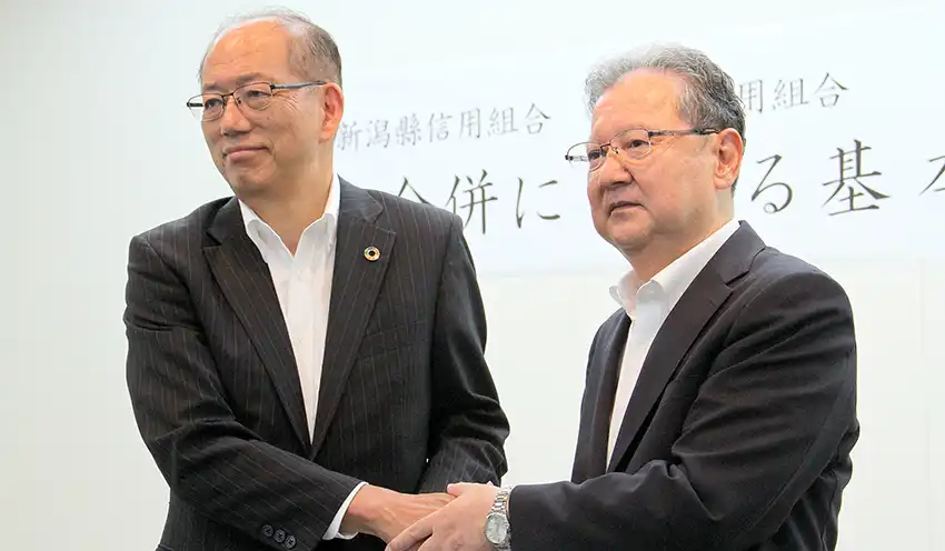 合併への基本合意を発表する赤川理事長（左）と清水理事長（8月7日、新潟県信組新潟駅前支店3階）