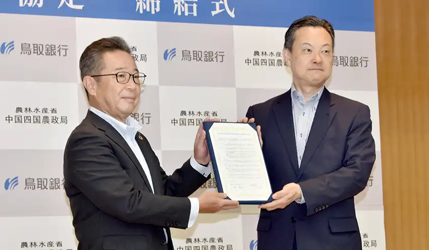 協定書を取り交わす農林水産省中国四国農政局の郷達也局長と入江頭取(左、8月8日、本店)