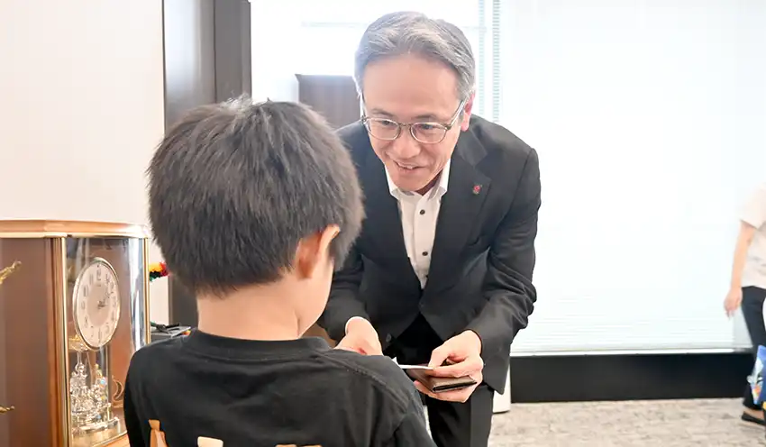 子どもと名刺交換する久米社長（8月18日、本社）