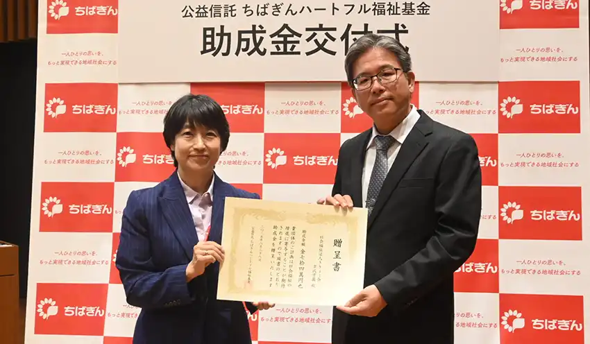 助成金授与証を手渡す淡路取締役専務執行役員（左、8月28日、本店）