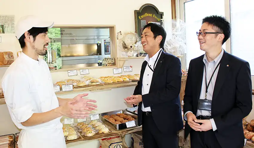 カフカ製パンを創業した倉田さん（左）と情報交換する堀支店長（中央）と岡音拓也・お客様担当融資推進役（7月10日、カフカ製パン）