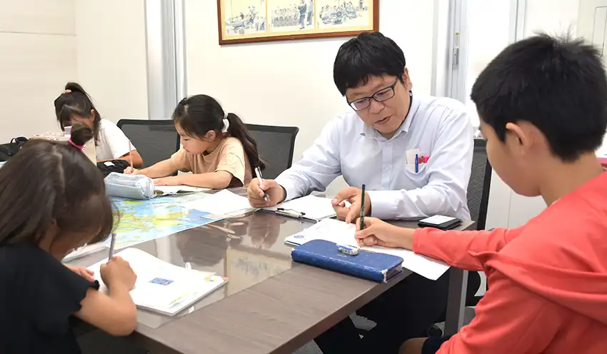 現役の塾講師から課題の解き方を教わる子供たち（8月22日、蒲原支店）