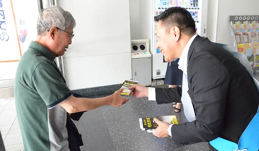 特殊詐欺防止のチラシとポケットティッシュを手渡す佐賀信金の高取部長（右、８月20日、佐賀駅）