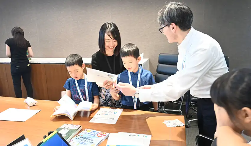 保険募集人（右）から保険証書の説明を受けるイベントに参加したキッズ社員（8月29日、東京本社）