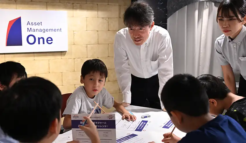 子どもたちと投資する会社について話し合う杉原社長(中央、8月29日、キッザニア東京)