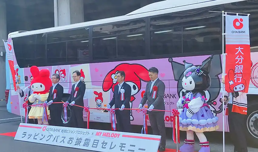 運行開始を祝しテープカットをする佐藤常務取締役（左から3人目、8月1日、大分県庁舎前広場）
