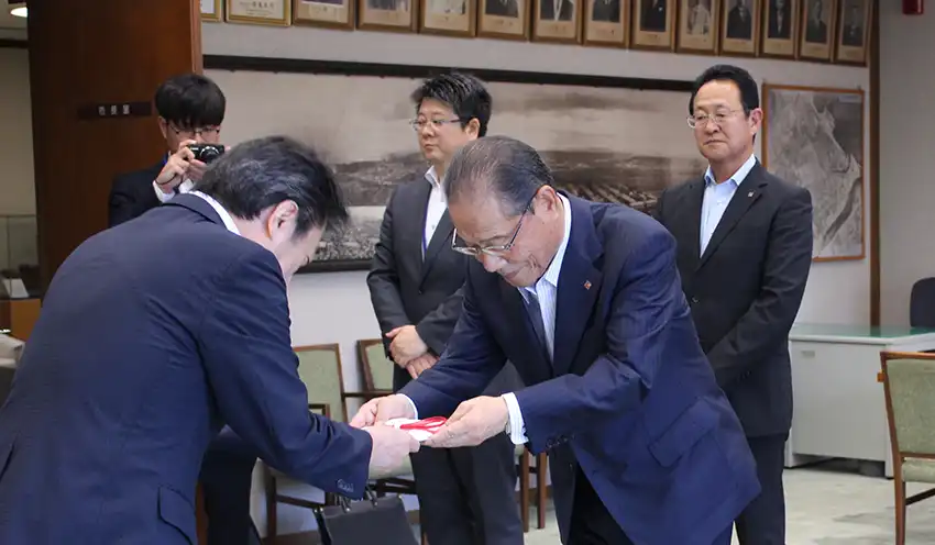 足立広域連合長に目録を手渡す吉野理事長（右、8月21日、大分市役所、大分県信組提供）