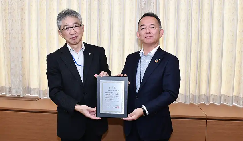 矢内本部長（左）から岸川専務に感謝状の盾が手渡された（8月20日、杜の都信金本店）