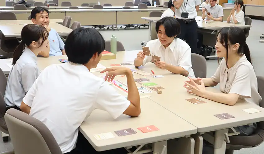 ゲームを楽しむ内々定者とやまなし地域デザインの佐藤優取締役（左奥、8月20日、山梨中央銀研修センター）