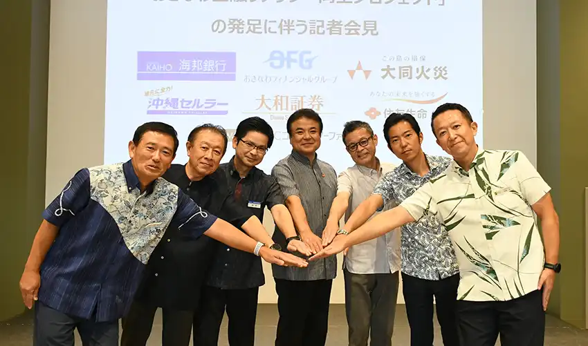 発足式に参加した伊波専務（中央）、﨑原専務（左から3人目）ら（8月1日、沖縄銀本店、おきなわFG提供）