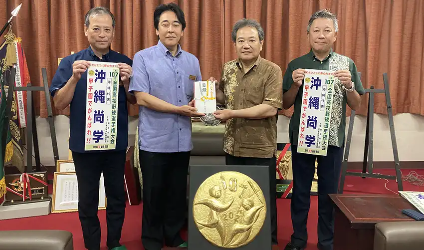 沖縄尚学高の末吉康徳校長（左から3人目）に寄付目録を渡す平岡常務執行役員（同2人目、8月18日、沖縄尚学高、琉球銀提供）