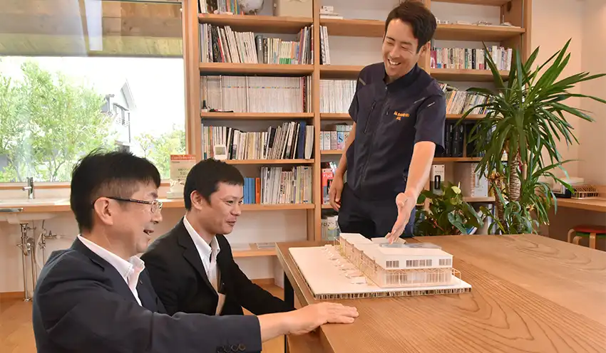 メイン先の岩見建設の一級建築施工管理技士・渡辺真也氏（右）からモデルハウスについて説明を受ける橋本支店長（左）と長島秀司支店長代理（8月5日、益田市）