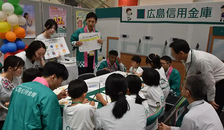 広島信金のブースでお小遣い帳の使い方を学ぶ参加者（8月24日、イオンモール広島府中）